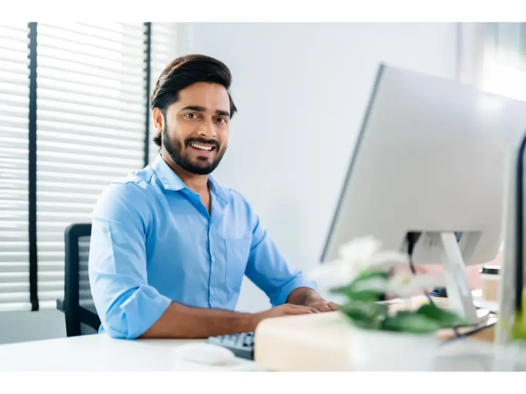 Busy man in a suit checking his computer while smiling, illustrating the convenience of aligners for working professionals.